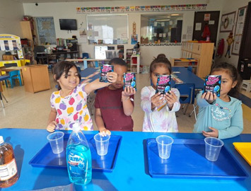 Kingston children exploring materials and cups at a classroom table