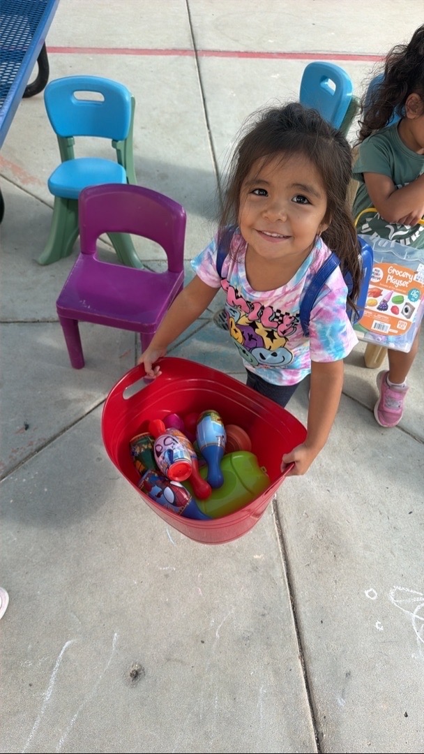 A child holding a basket of pretend food outside