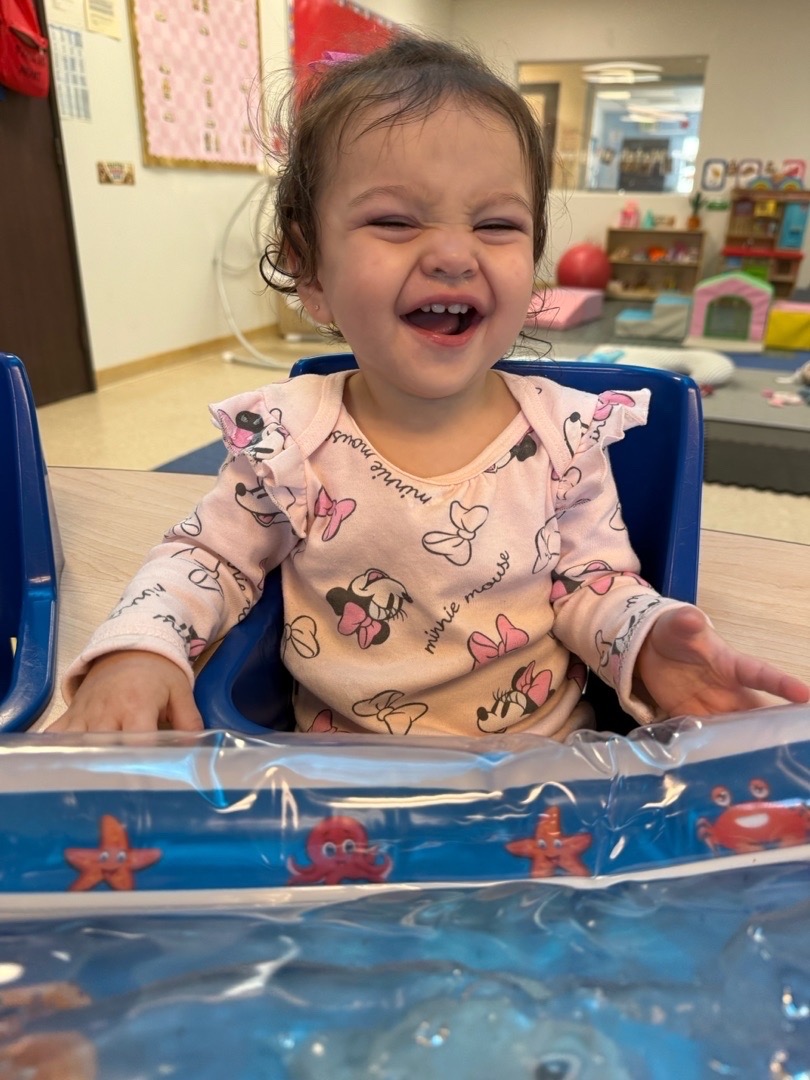 A laughing child exploring a sensory water mat