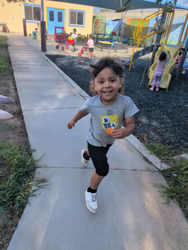 A smiling child running along the playground path