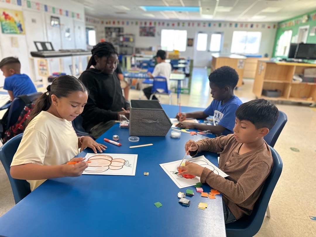 Children creating colorful pumpkin artwork at a classroom table