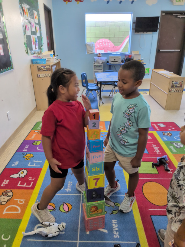 Children standing beside their tower of numbered blocks